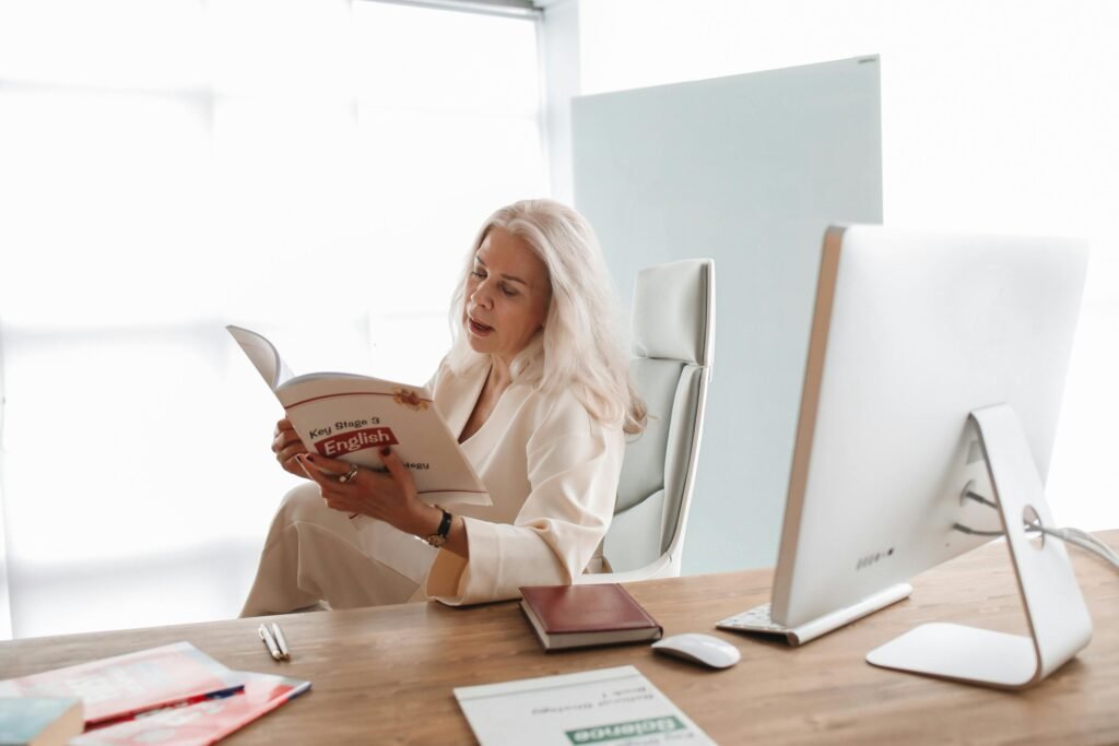 Woman in office reading an English book, focused and studying.